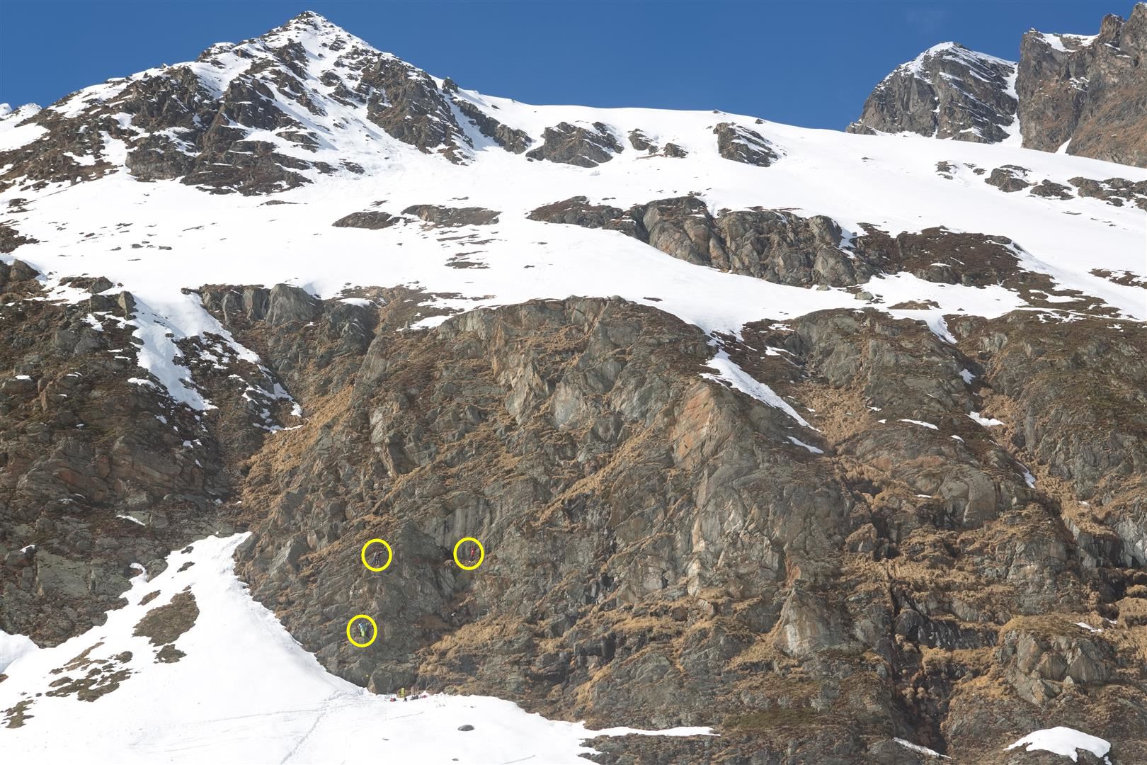 Die gelben Kreise zeigen die Personen im Klettersteig nahe der Franz-Senn-Hütte. Darüber ein Hang mit Rissen sowie Aufwölbungen in der Schneedecke, welche auf vermehrtes Schneegleiten hindeuten. (Foto: 19.03.2024) © Horst Fankhauser.