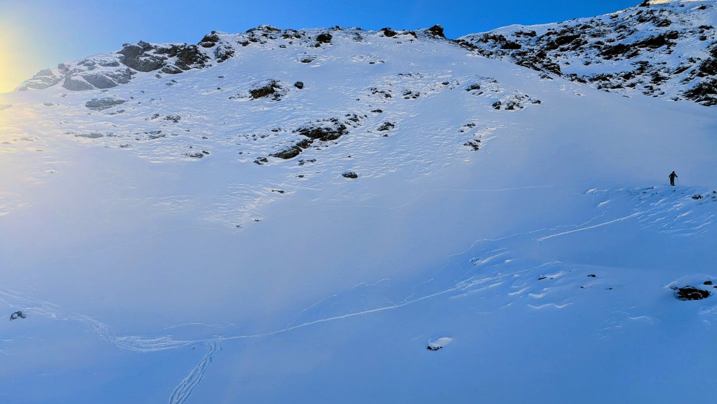 Beim Betreten der Schneedecke ertönte ein Wummgeräusch- Ebenso bildeten sich Risse in der Triebschneelinse. Die Risse erkennt man u.a. links des Tourengehers bzw. etwas oberhalb der Skispur, welche von links nach rechts ansteigt. Sellrain. (© Fynn Renner, 04.01.2026)